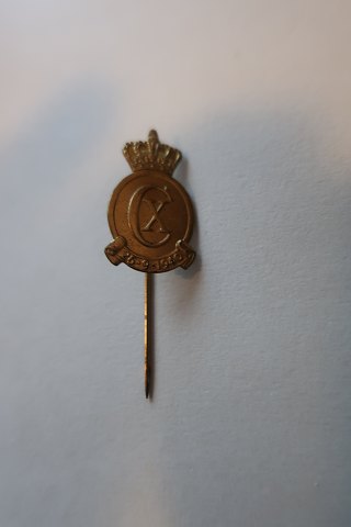 For samlere:Ældre reversnål / KongeemblemUdført i gult metal med bogstaverne CXFremstillet efter en tegning af Poul Søbye (1889-1965)Dateret: 26.9.1940L: 4cm
