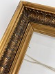 Old wooden gold frame with leaves and glass from 
the beginning of the 20th century