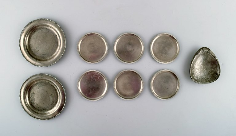 Just Andersen. En samling på otte art deco flaskebakker og et lille fad i tin. 1930