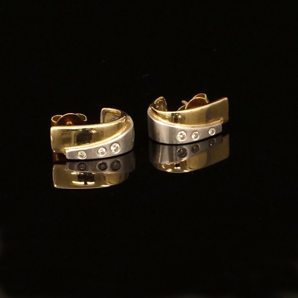 A pair of 14kt gold earrings each with three diamonds of circa 0,04ct. Size: 14x6mm