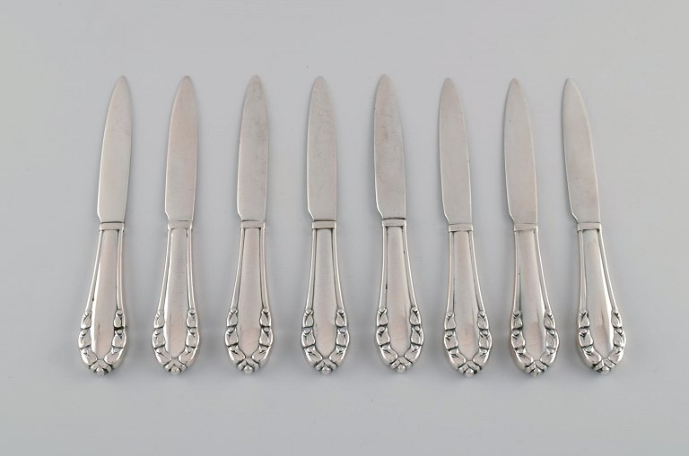 Otte tidlige Georg Jensen Liljekonval frugt / smørknive i helsølv (830). Dateret 1915-1930.