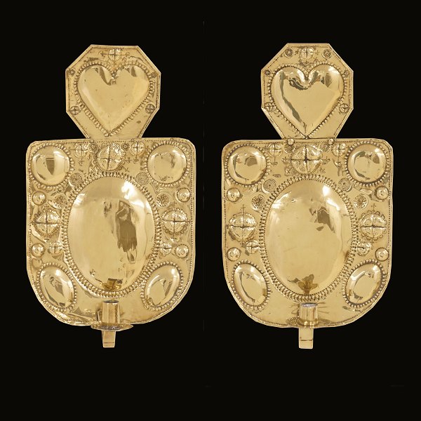 Et par vægskjolde i messing hver til ét lys. Topskjold dekoreret med hjerte. Danmark ca. år 1850. H: 46cm. B: 26cm
