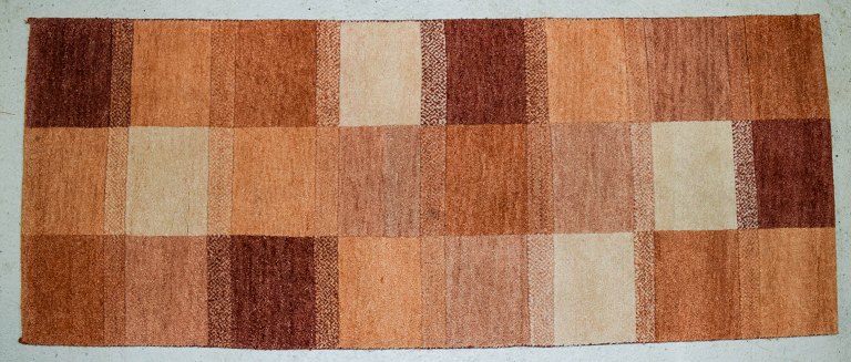 Milford, Sverige, tæppe i ren uld. Geometriske felter i røde, orange, og hvide 
nuancer. 1970