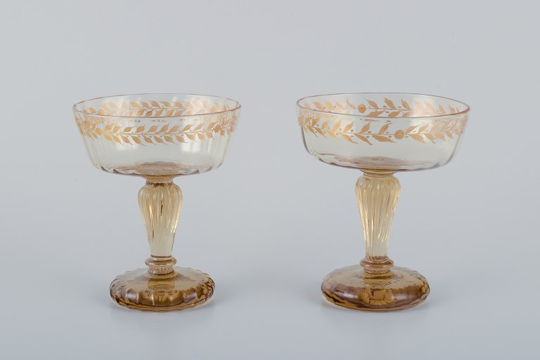 Emile Gallé (1846-1904), French artist and designer.Two champagne coupes in crystal glass hand-decorated with gold leaf motifs.
