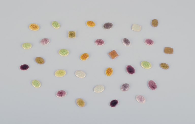 Ole Bjørn Krüger (1922-2007), dansk billedhugger og keramiker. 32 unika brocher i glaseret stentøj i lilla, hvide, gule og grønne nuancer.