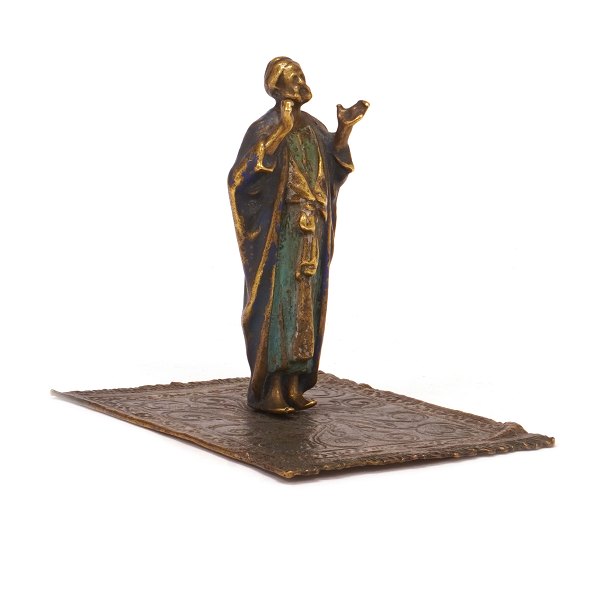 Figurine in the shape of a man on a carpet. H: 9,5cm. Base: 9x11cm